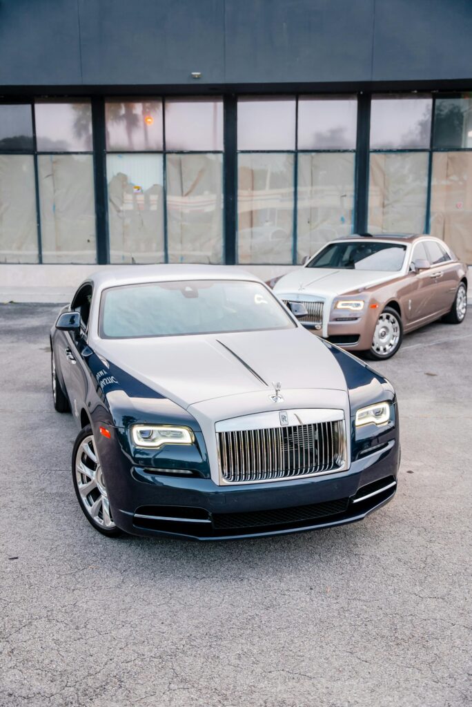 Two Rolls-Royce Wraith vehicles in front of a modern building, showcasing luxury design.