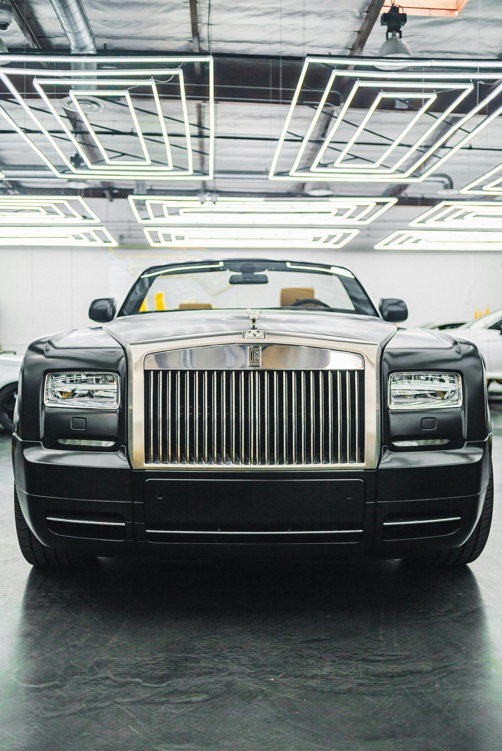 Front view of a classic luxury Rolls-Royce car in a modern indoor exhibition.